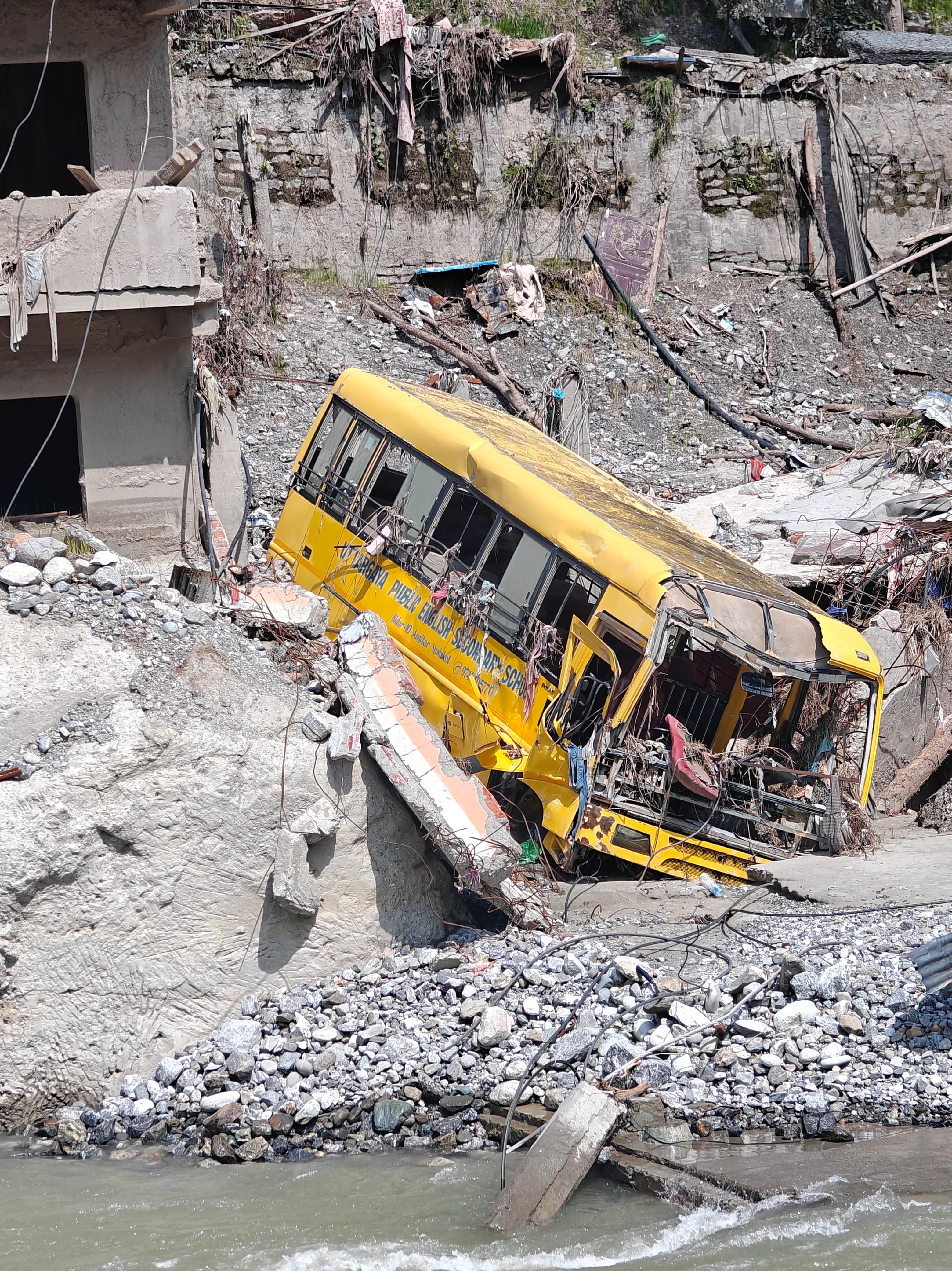 A yellow school bus surrounded by flood debris in Rasuwa, Nepal